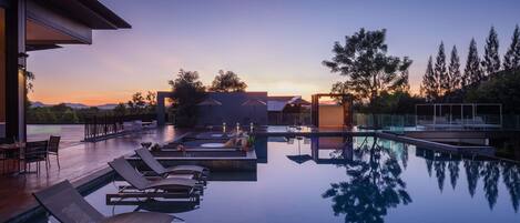 A modern pool area with lounge chairs and a clear view of the sunset.