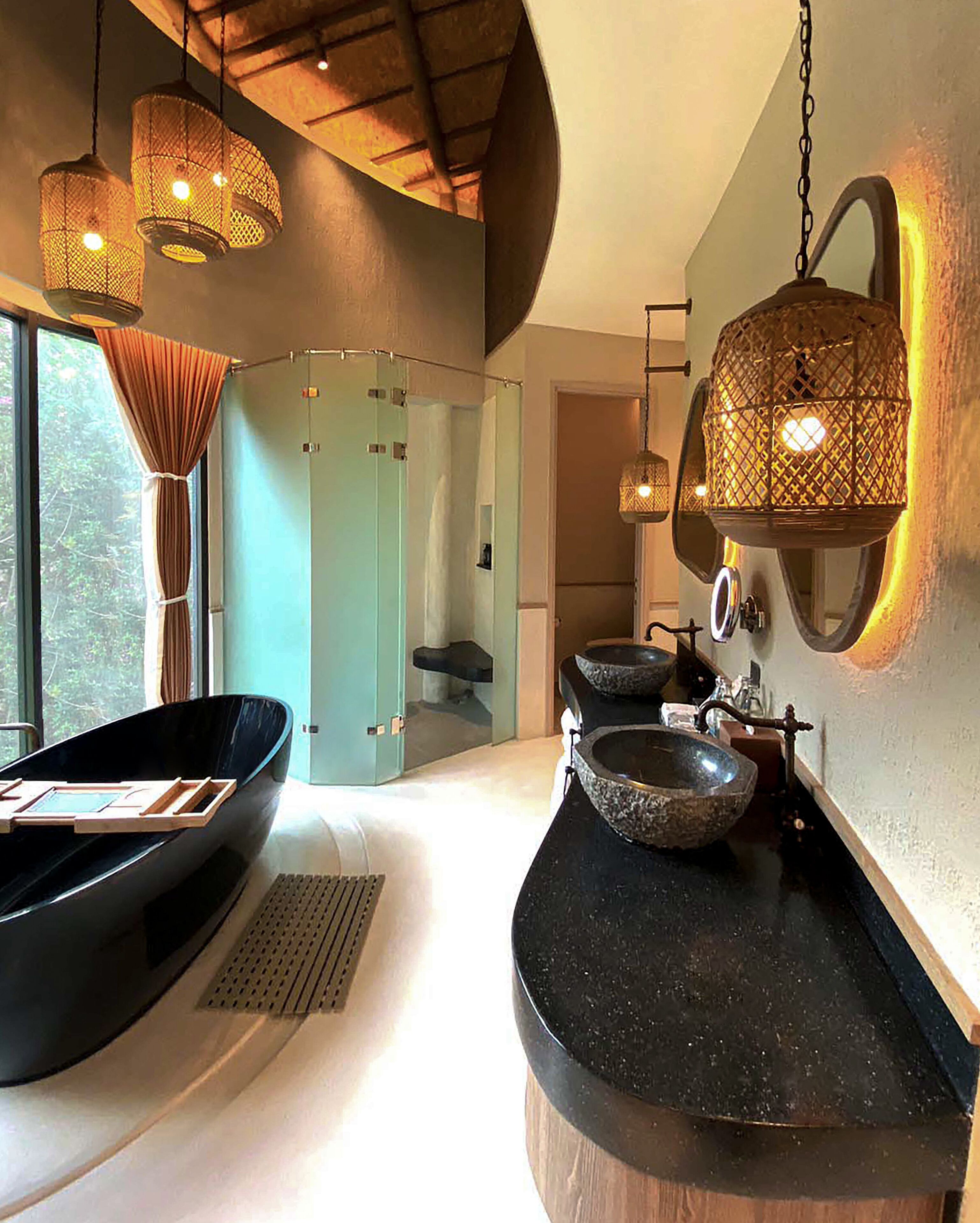 A modern bathroom with a large bathtub, two sinks, and hanging light fixtures.