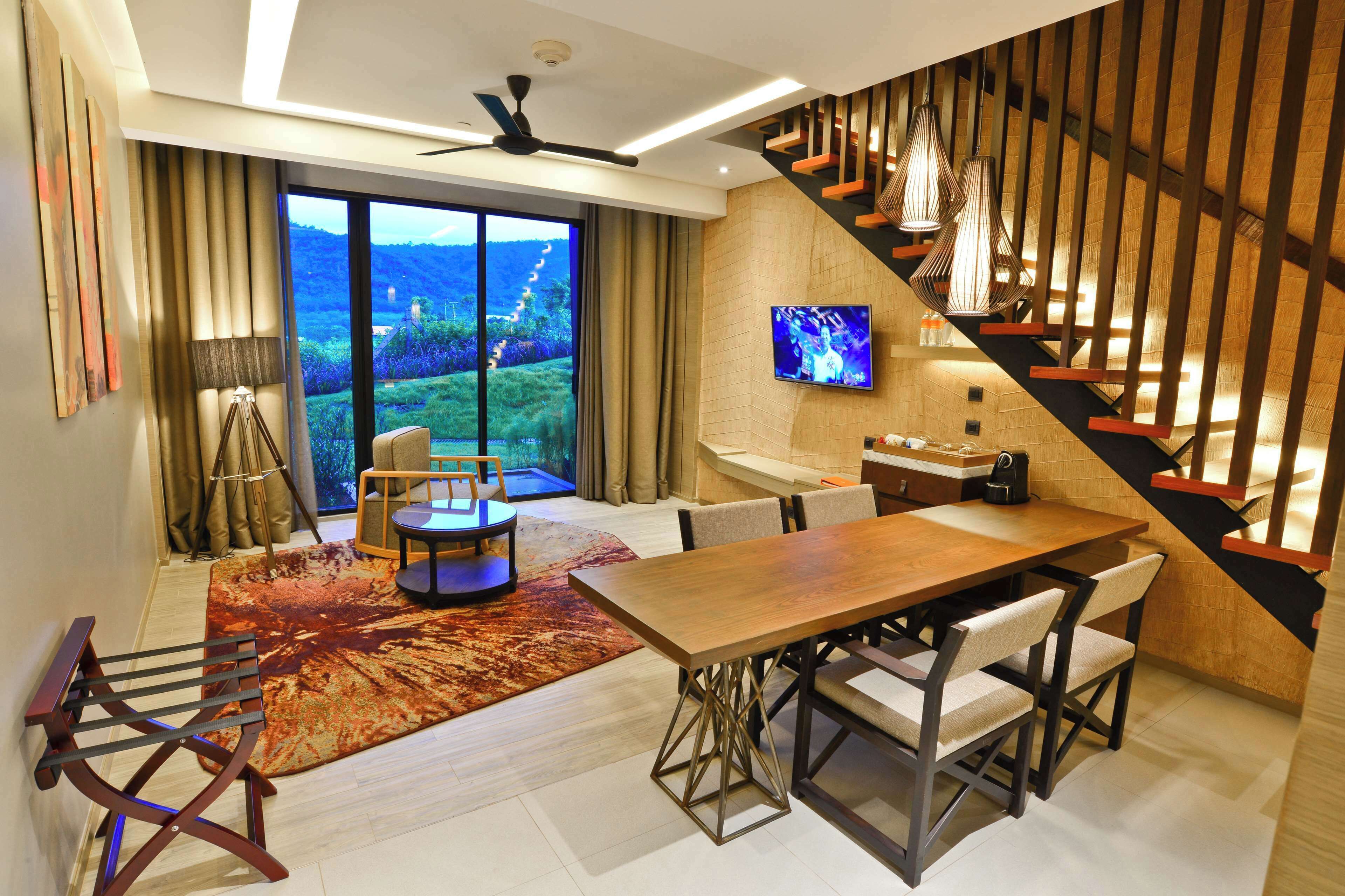 Una sala de estar moderna con una mesa de comedor de madera, un sofá y un amplio ventanal con vistas panorámicas.