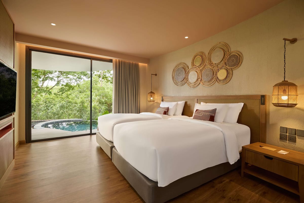 A modern hotel room with a large bed, a TV, and a view of a swimming pool.