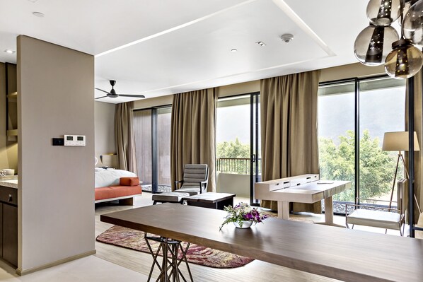 Una habitación de hotel moderna con una cama grande, una mesa de comedor y un balcón con vistas.