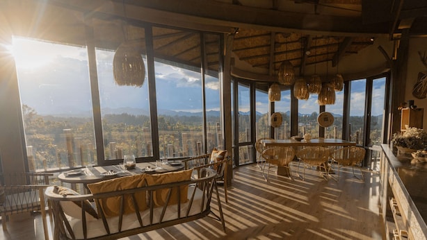 A spacious dining area with a high ceiling and large windows offering a panoramic city view. - dusitD2 Khao Yai (Pak Chong)