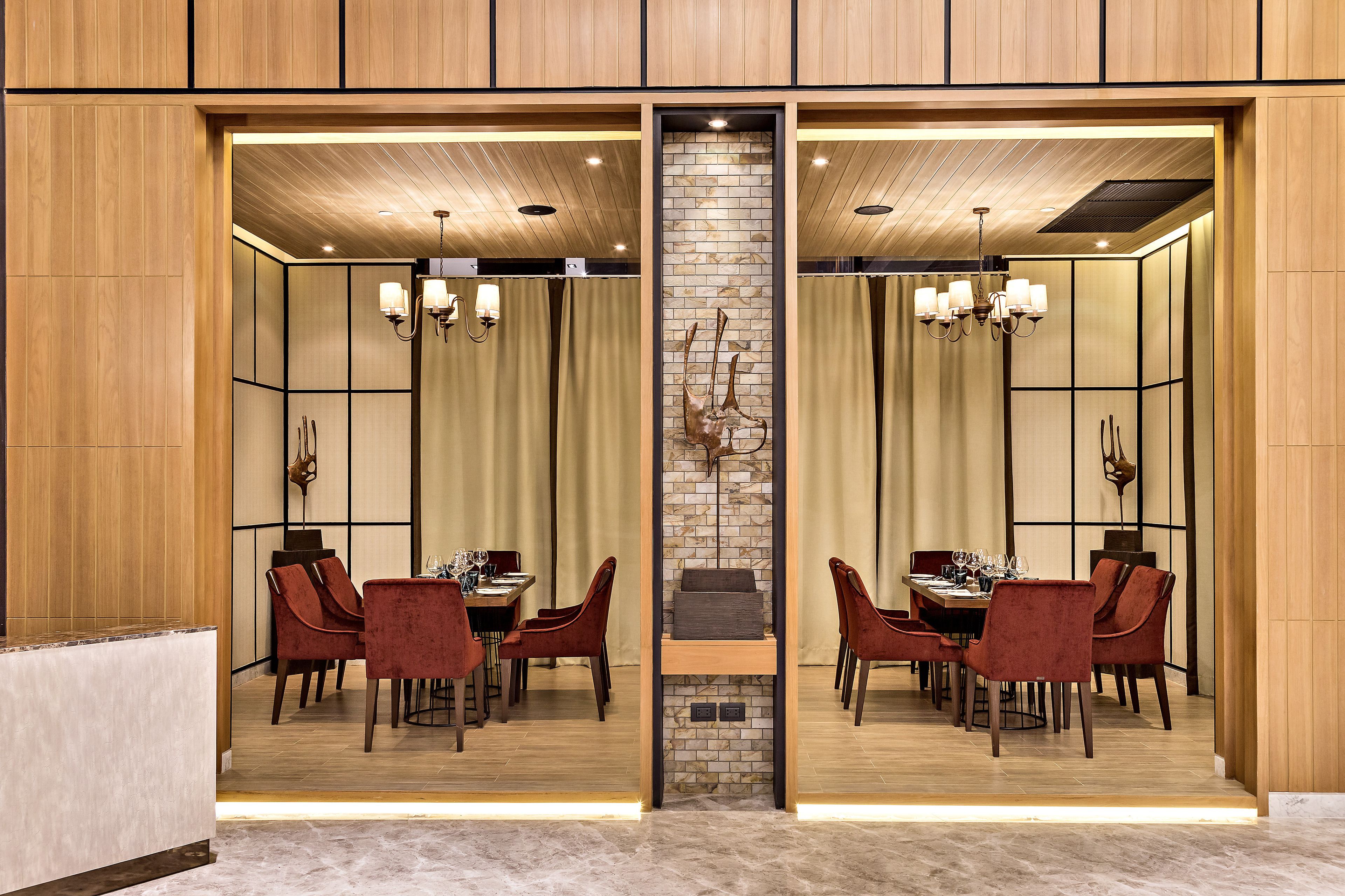 A modern dining area with a mirrored wall, wooden paneling, and a central brick accent wall.