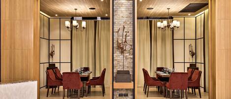 A modern dining area with a mirrored wall, wooden paneling, and a central brick accent wall.