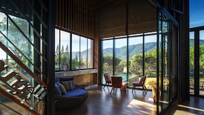 A modern interior with large windows, a wooden floor, and a seating area with a sofa and chairs. - dusitD2 Khao Yai (Pak Chong)
