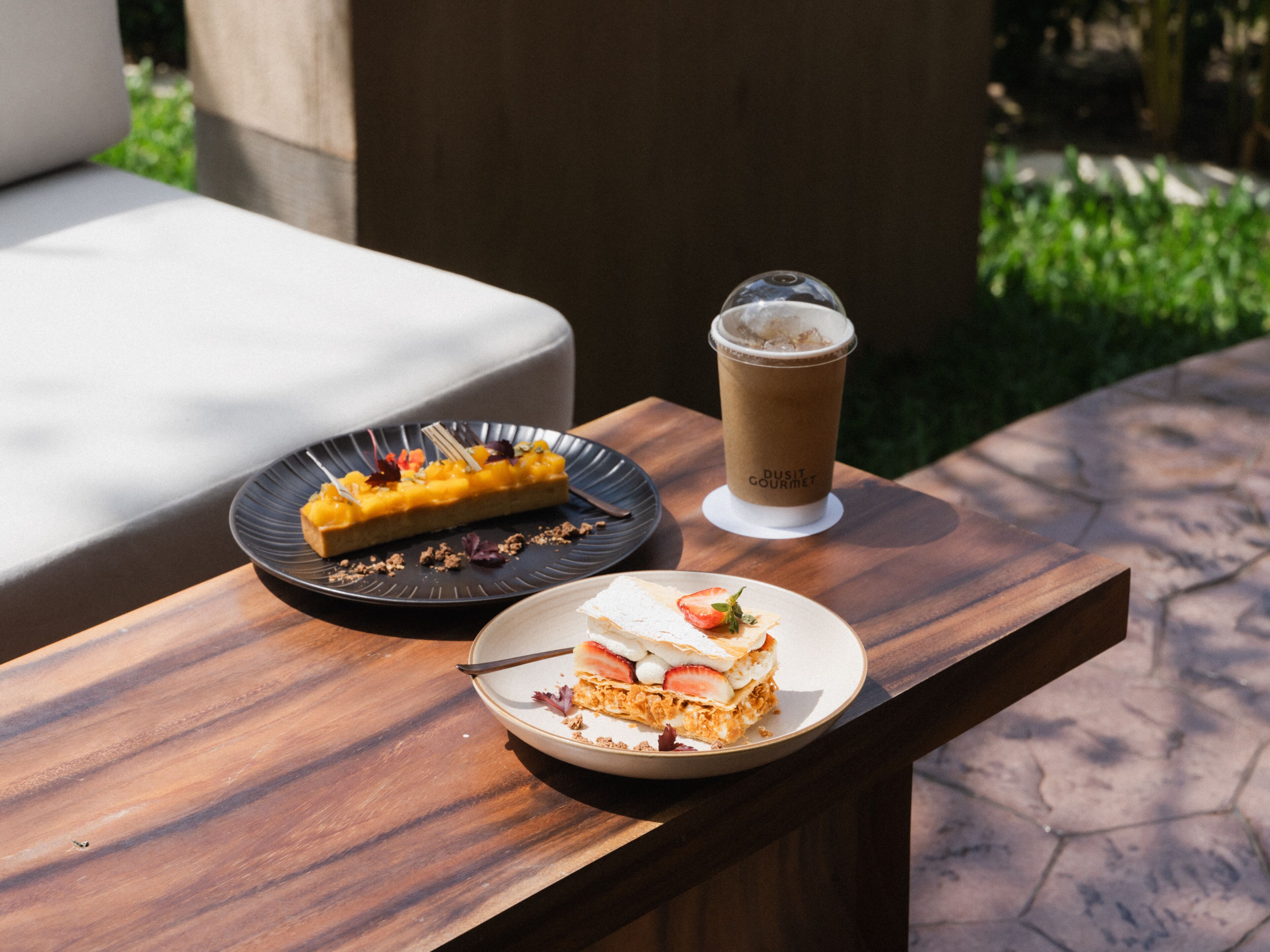 A wooden table with a dessert plate, a cup of coffee, and a slice of cake.