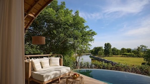 A bedroom with a view of a swimming pool and a river. - dusitD2 Khao Yai (Pak Chong)