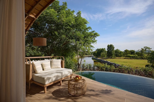 A bedroom with a view of a swimming pool and a river.