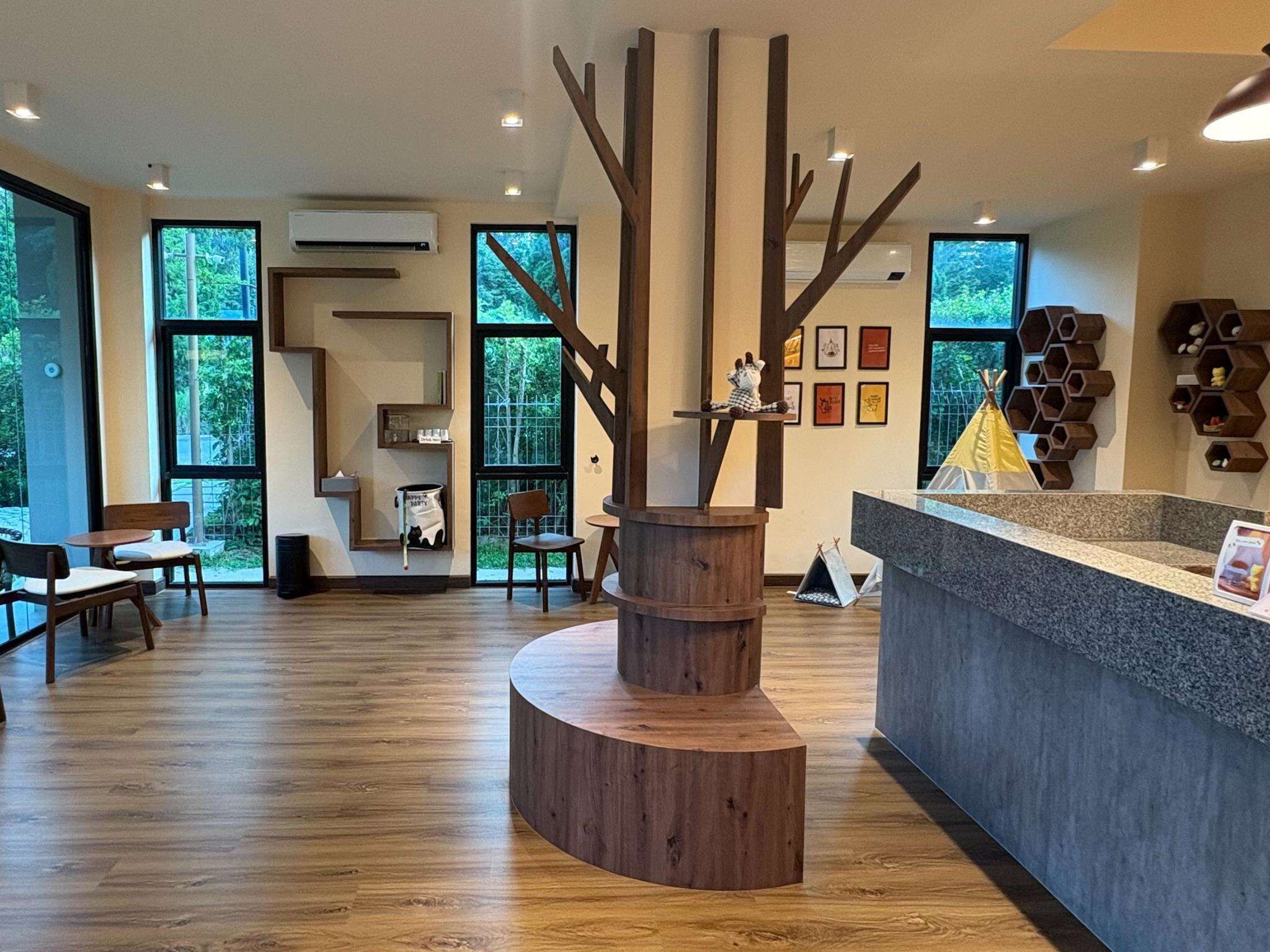 A modern reception area with a wooden sculpture centerpiece, large windows, and a counter with a grey countertop.