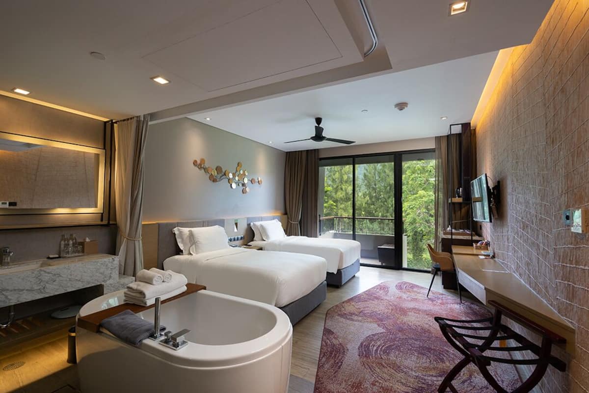A modern hotel room with two beds, a large bathtub, a desk, and a TV.