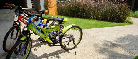 A green bicycle parked on a concrete path next to a building with a signboard.