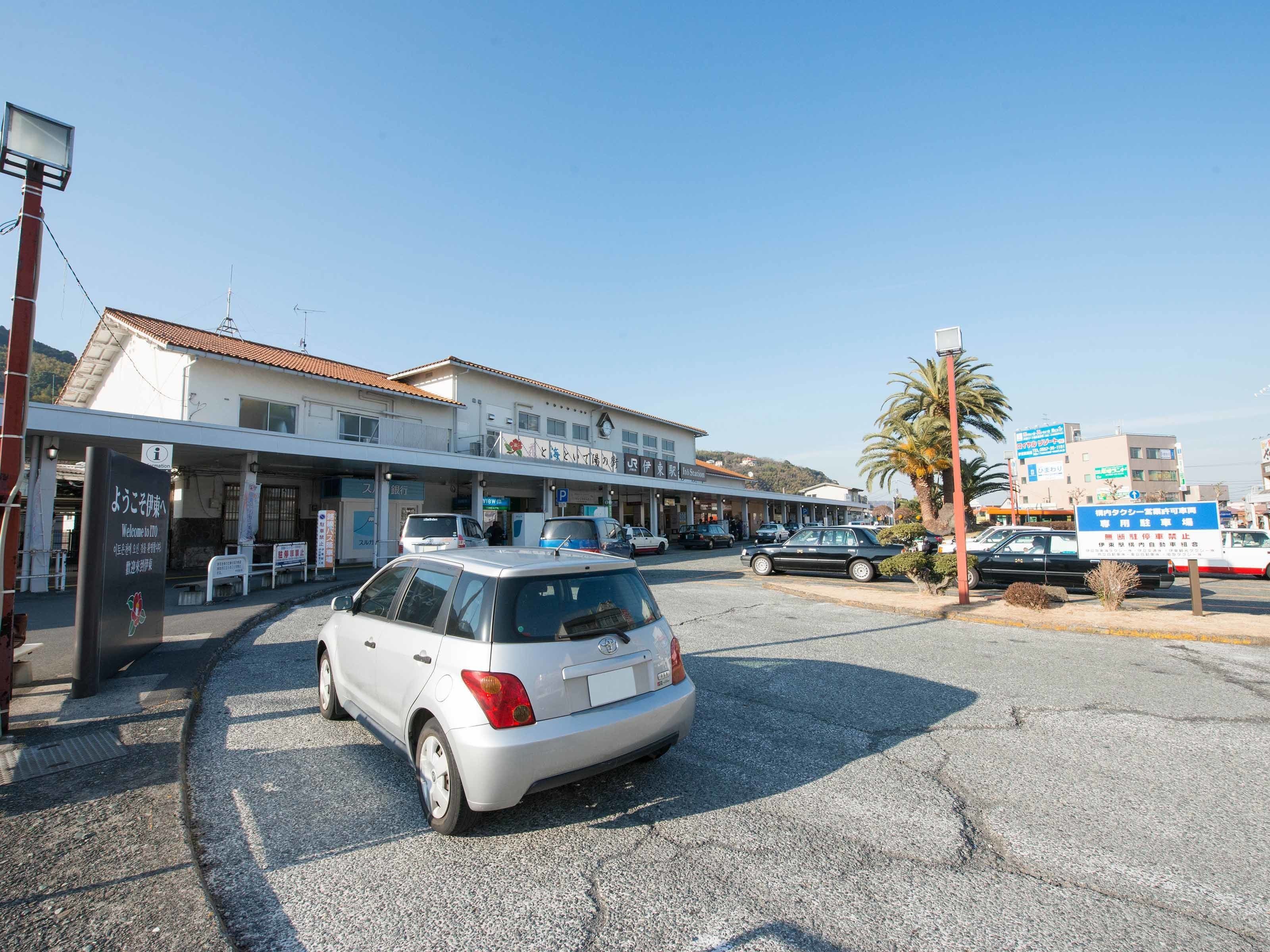 A parking lot with a white car, a building with a sign that reads "Welcome to XYZ", and a palm tree in the background.
