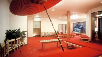 A room with red cushioned seating, a wooden bench, and a red umbrella.