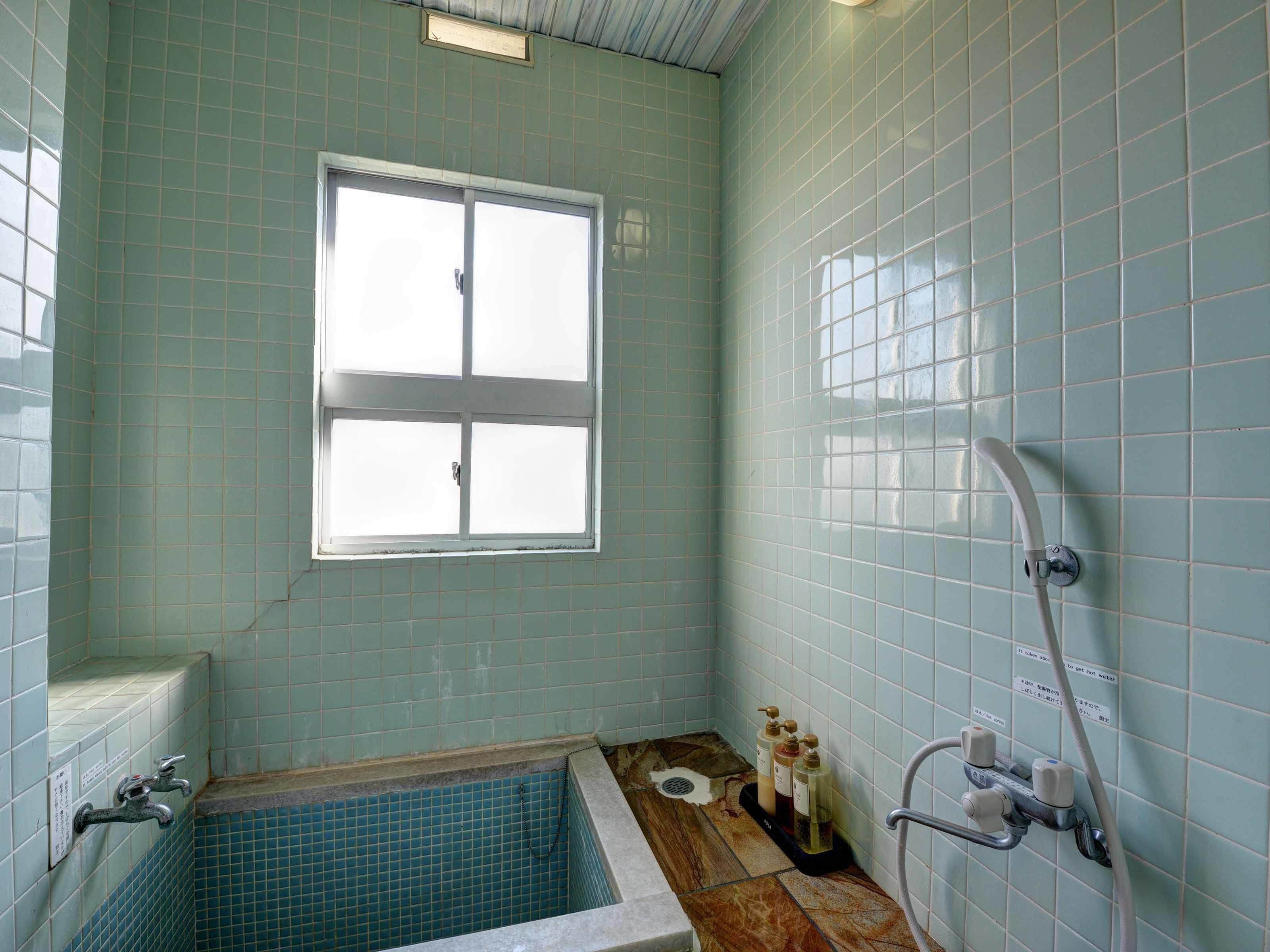 A bathroom with a bathtub, a window, and a shower.