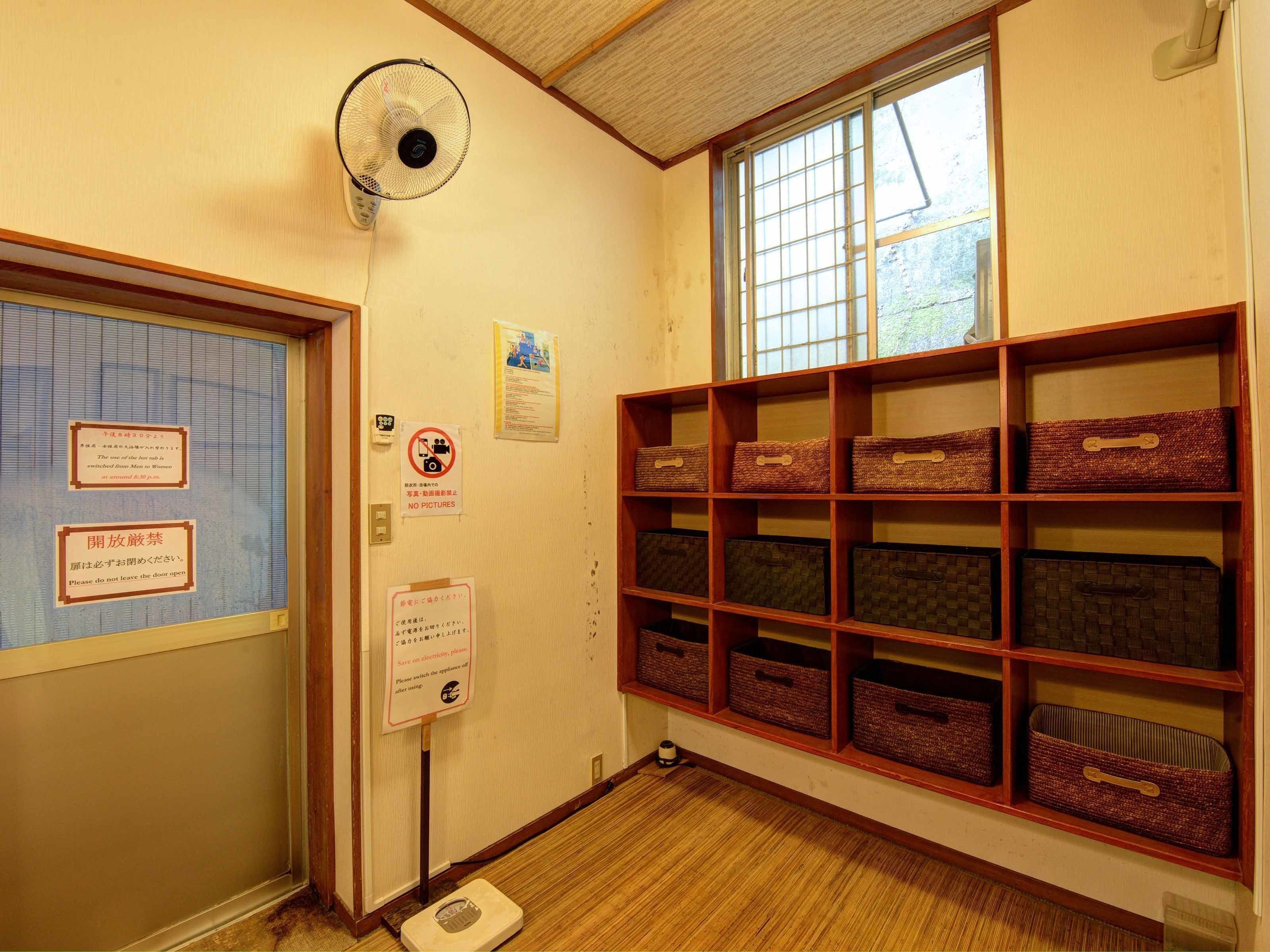 A room with a wooden floor, a window with a view, and shelves with storage boxes.