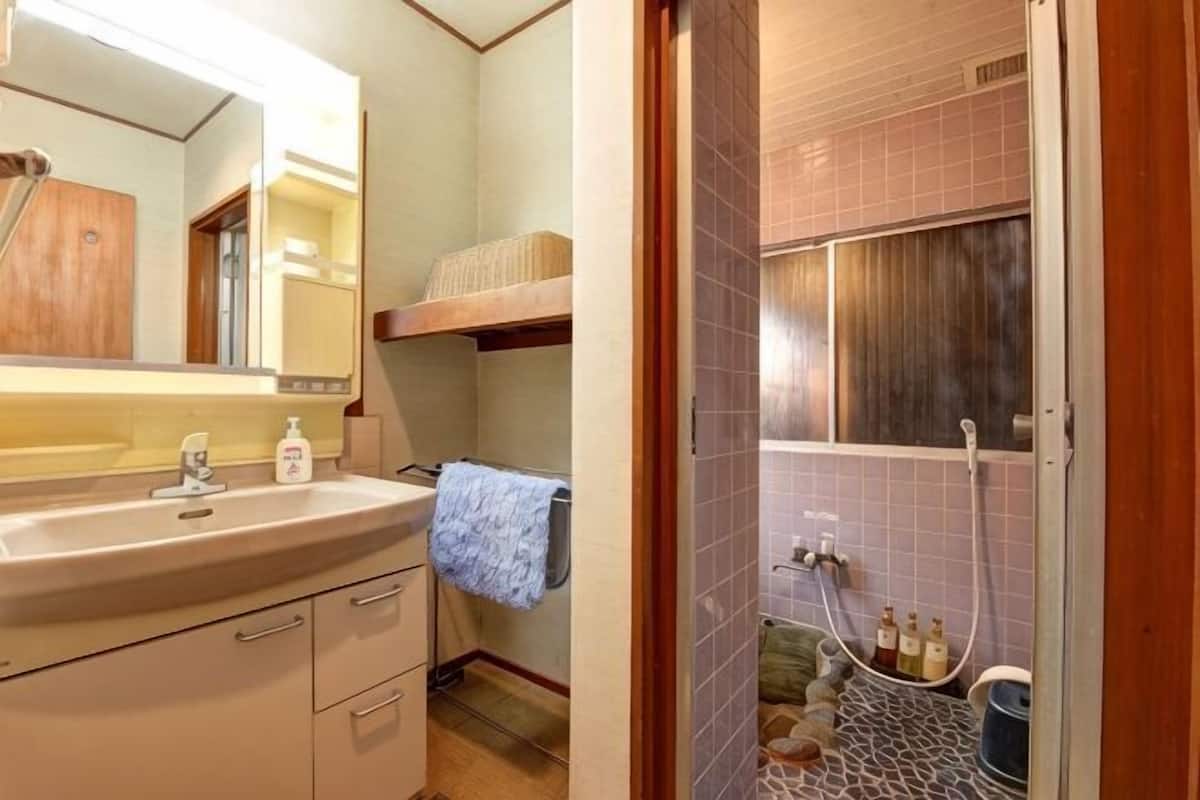 A bathroom with a sink, mirror, towel rack, and shower area.
