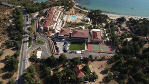 Vista aérea de un complejo turístico costero con varias edificaciones, una piscina y una zona de playa.
