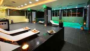 Un moderno espacio de spa con sillones reclinables, suelo calefaccionado y piscina.
