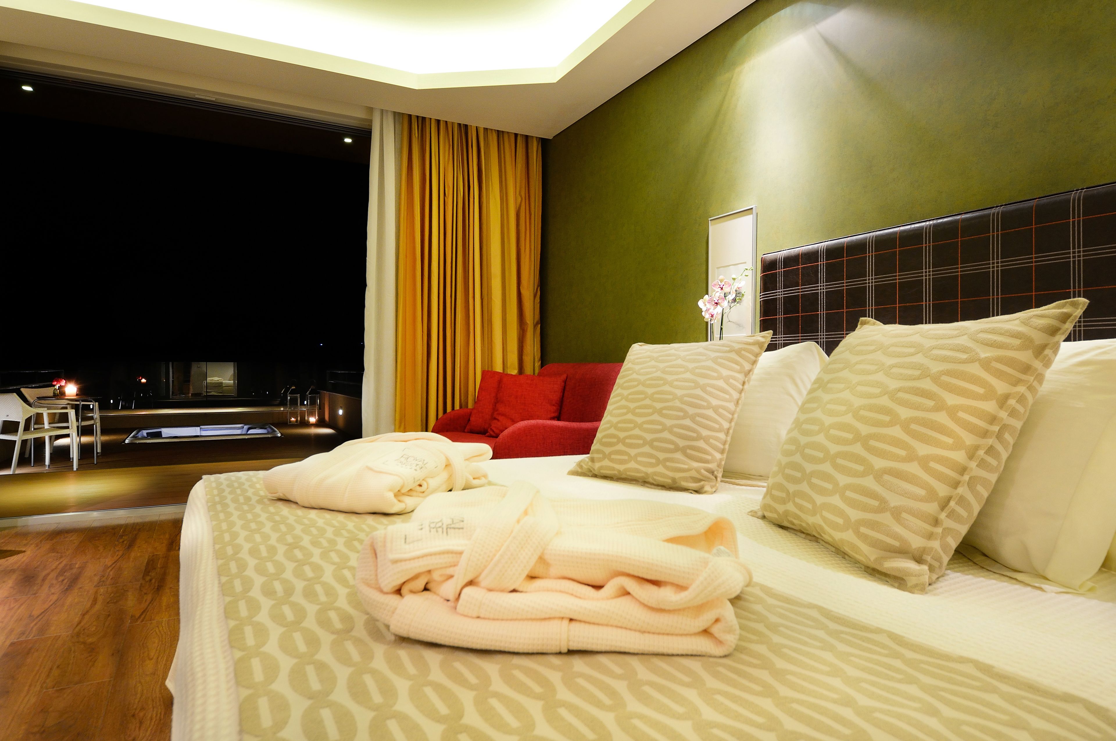 A hotel room with a large bed, a red chair, and a view of the night sky.