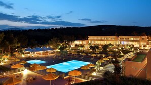 Un resort con piscina, mobiliario exterior y un edificio con amplias ventanas.