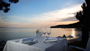 Mesa dispuesta para comer, con vista al mar y al atardecer.