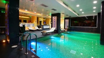 Una piscina techada, una piscina al aire libre, sombrillas