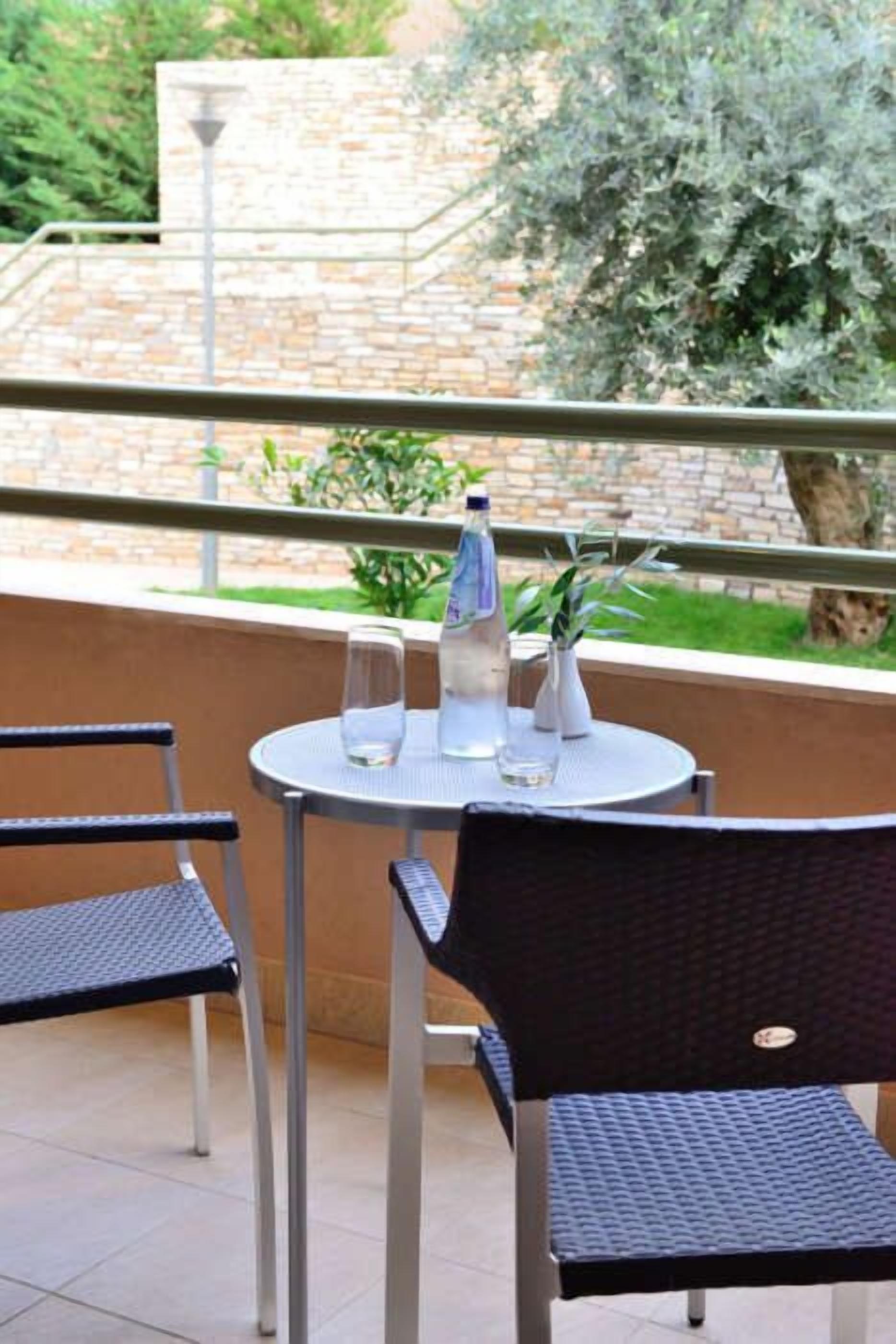 A round table with two chairs, a water bottle, and a glass on it.