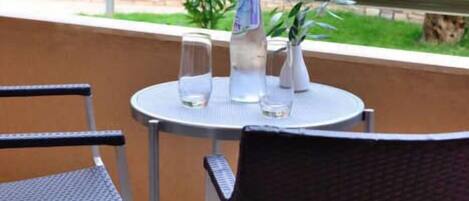 A round table with two chairs, a water bottle, and a glass on it.