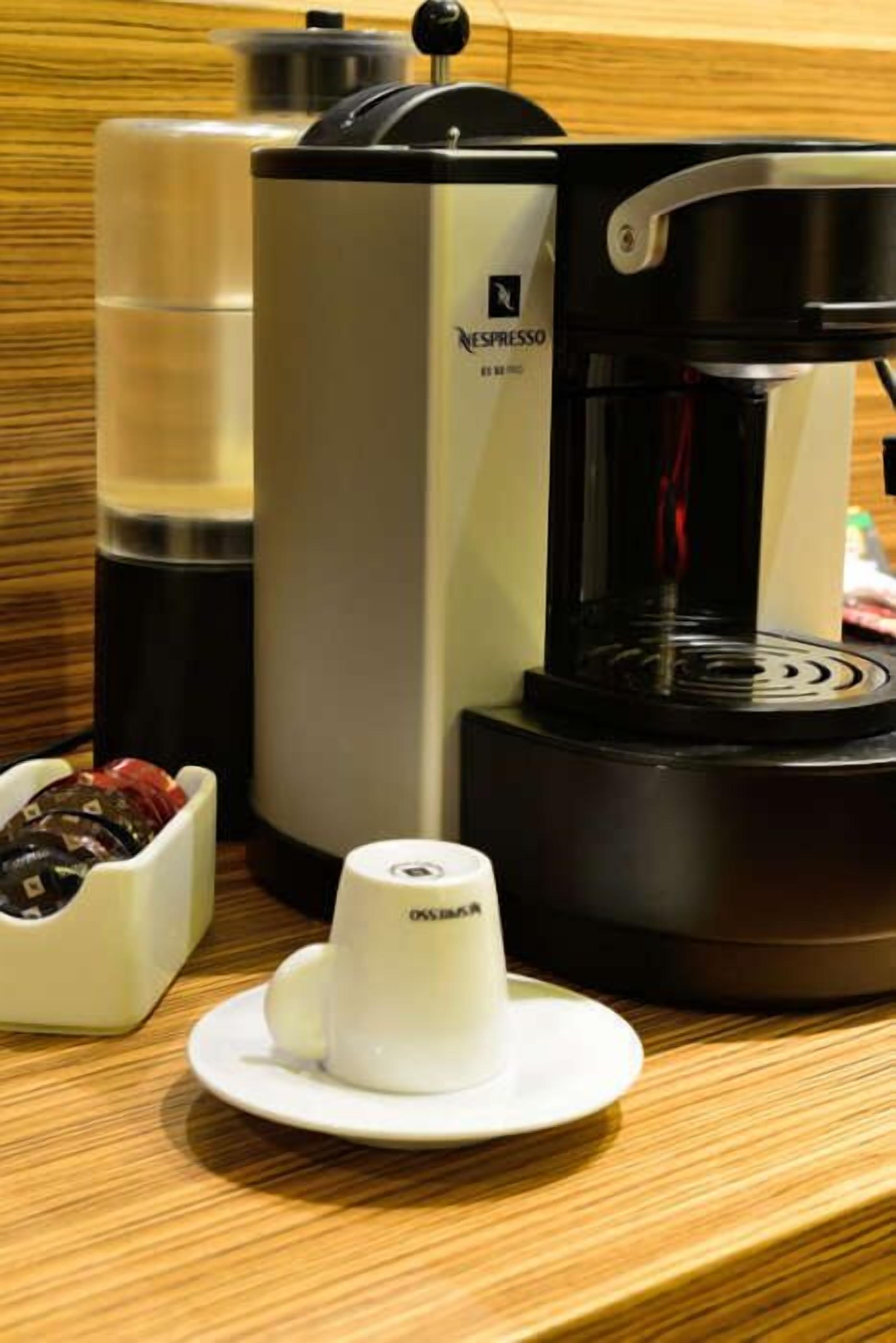 Una máquina de café Nespresso con una taza de café sobre un platito.