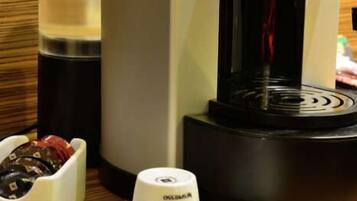Una máquina de café Nespresso con una taza de café sobre un platito.