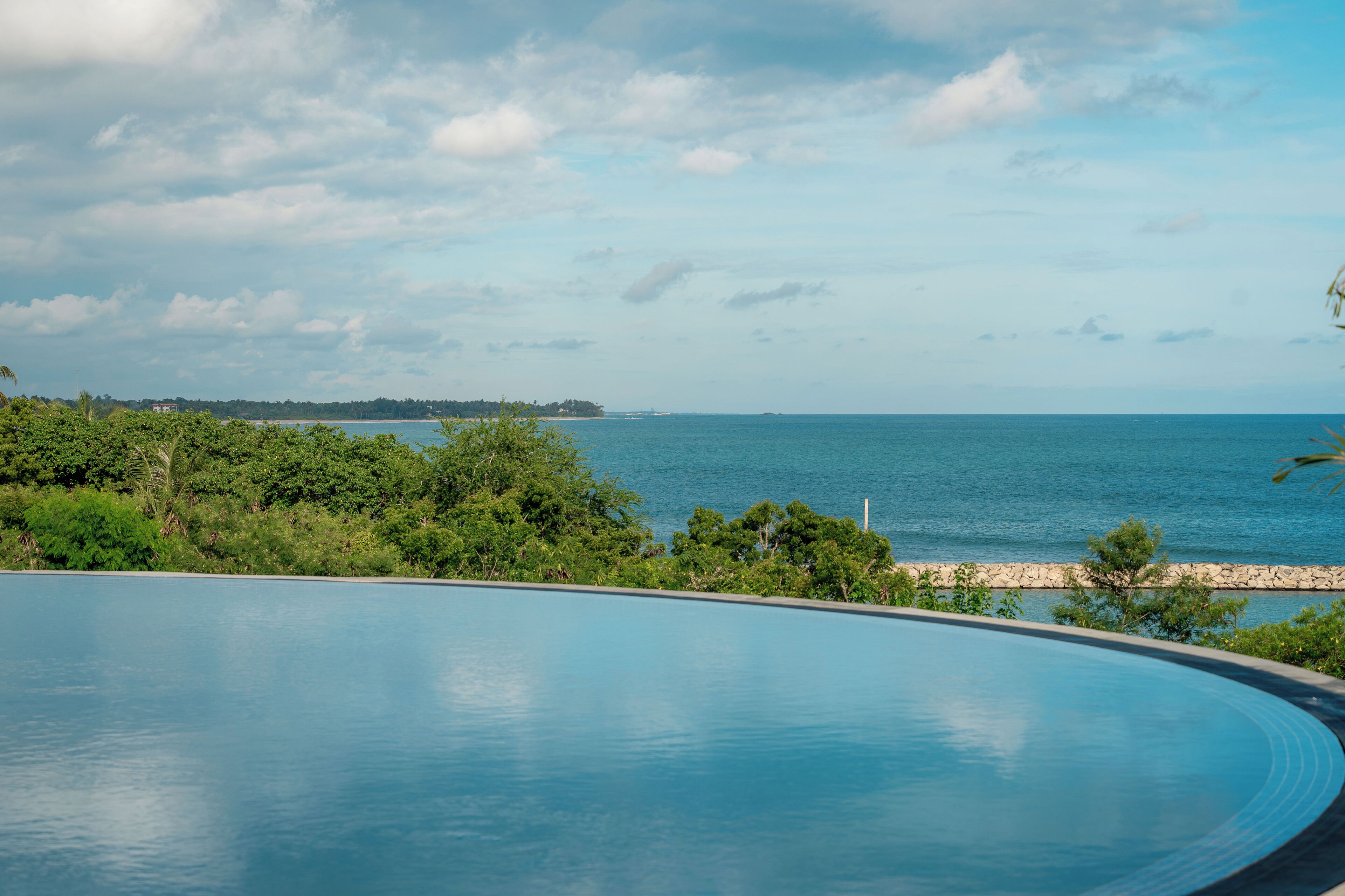 A swimming pool with a view of the ocean and distant land.