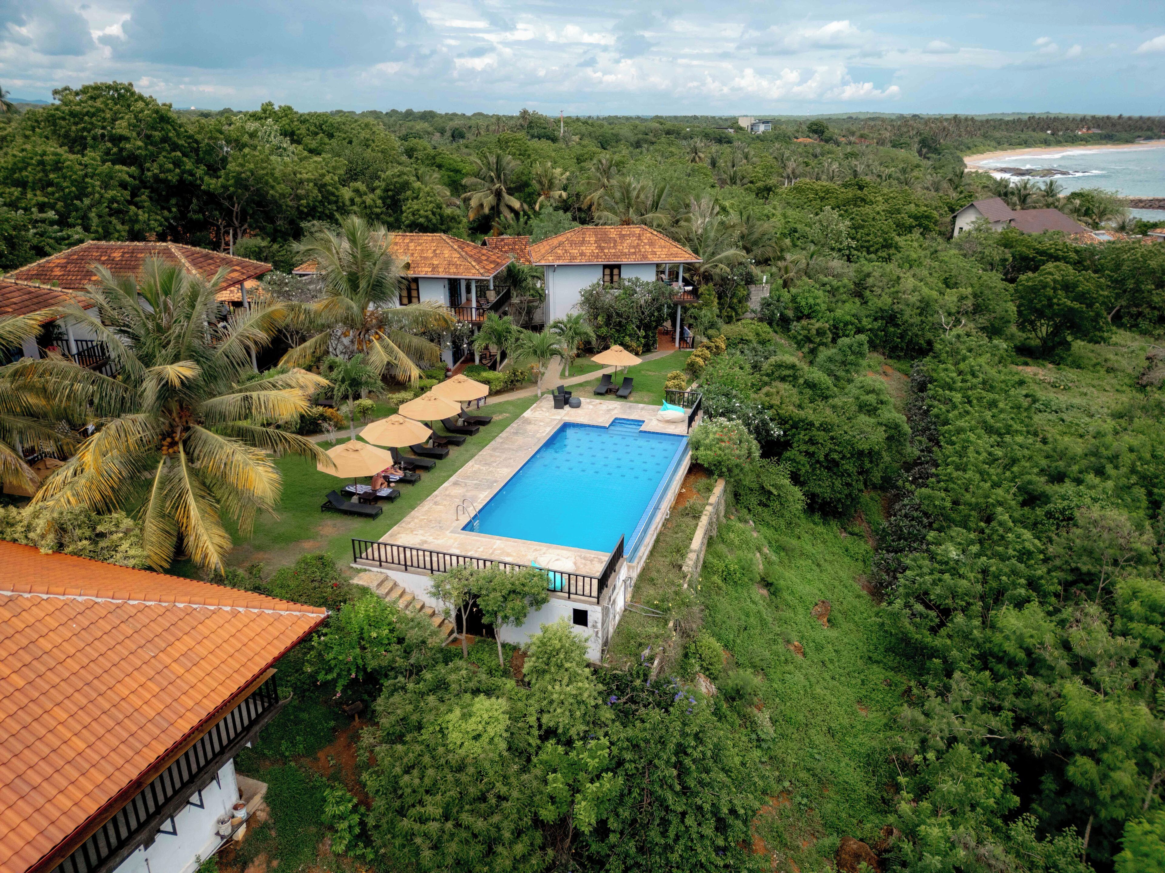 Un resort con piscina, sillones de descanso y vistas a la playa.