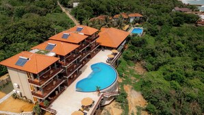 Un resort con varias edificaciones, una piscina central y abundante vegetación.