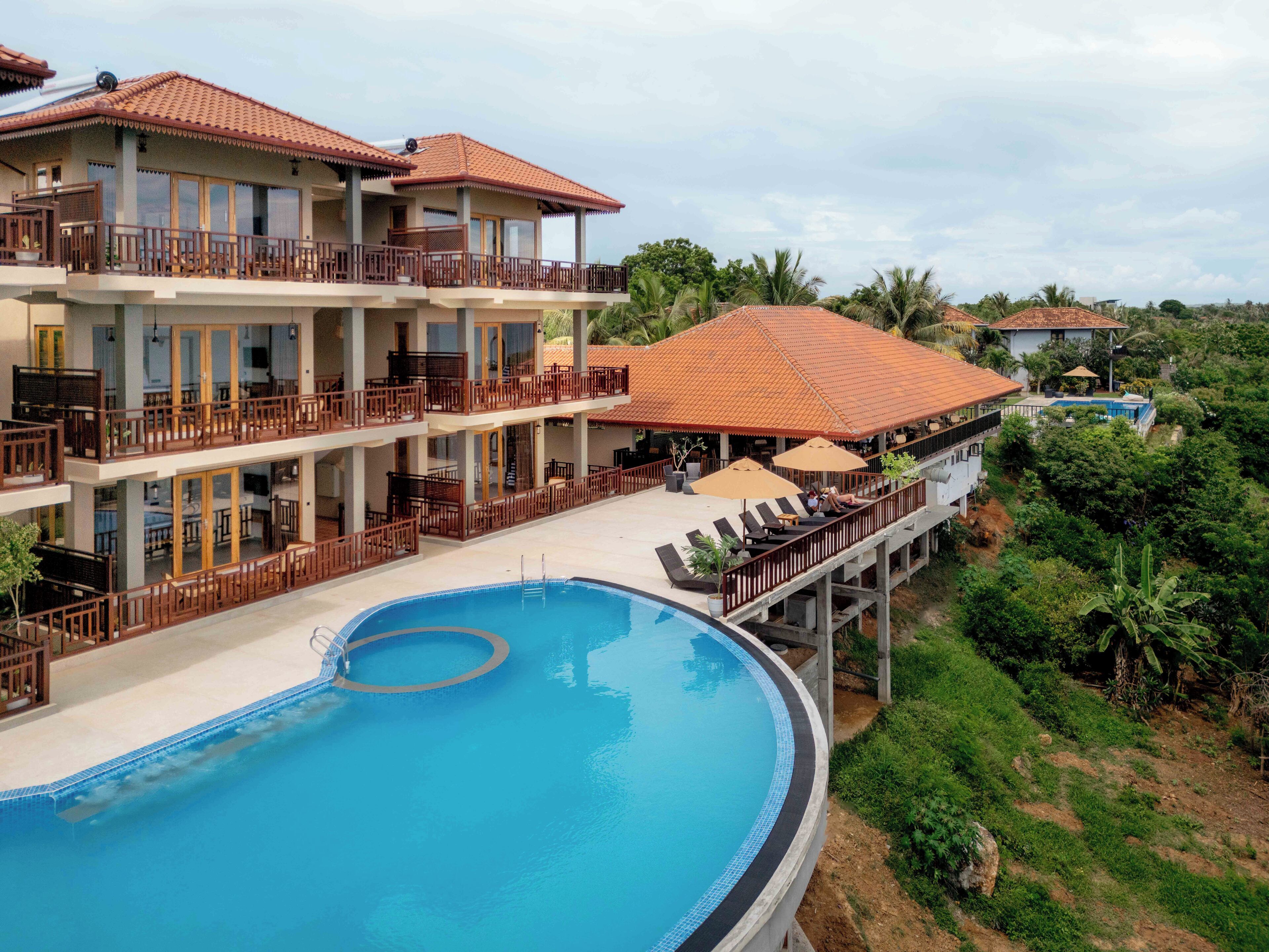 A hotel with a swimming pool, multiple balconies, and outdoor seating areas.