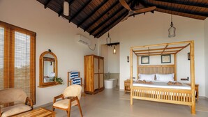 Una habitación amplia con una cama grande, muebles de madera, un baño y vistas a través de una ventana con persianas.