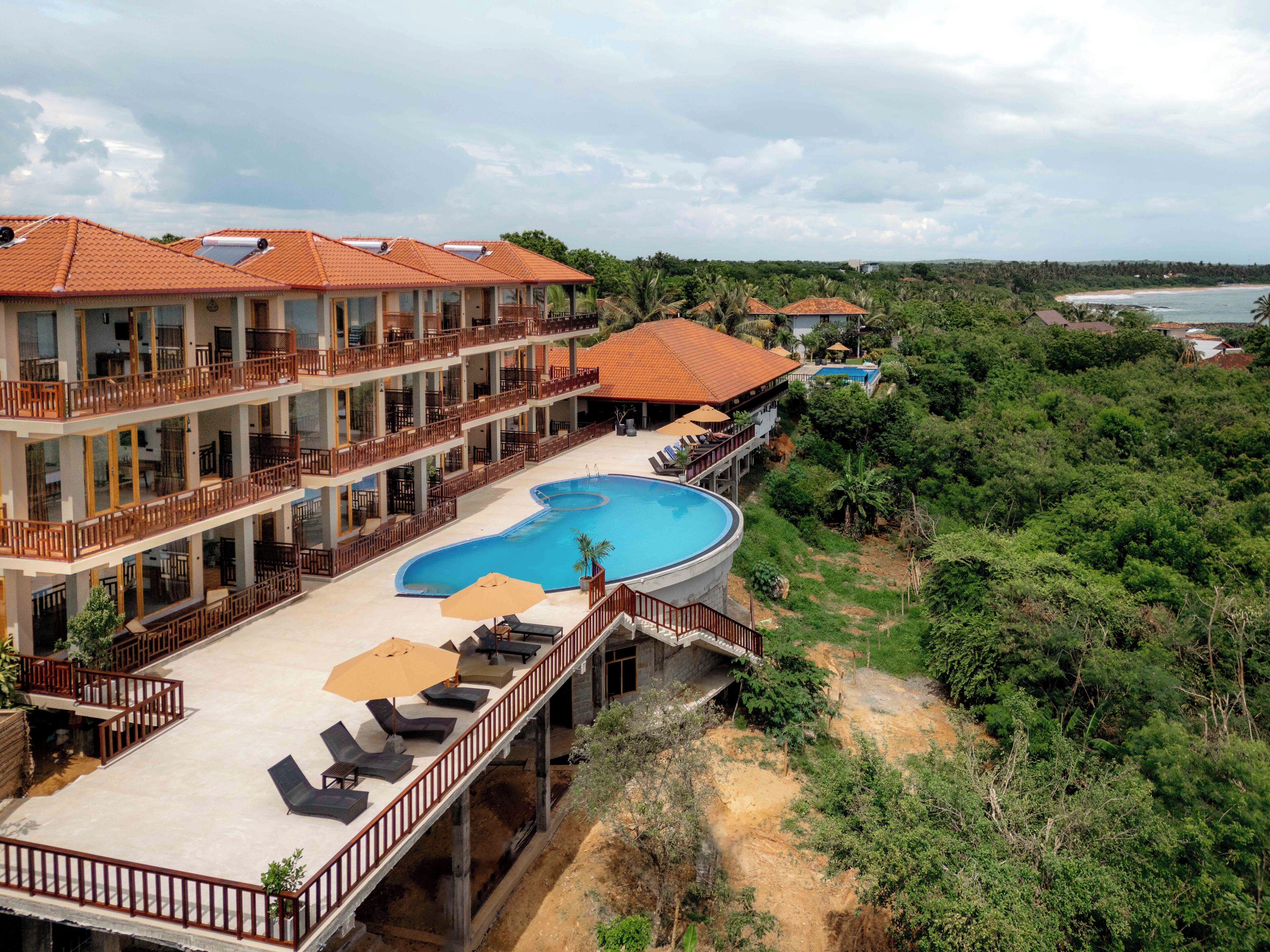 Un hotel de varios pisos con piscina, balcones y vista a la playa.