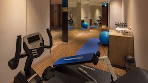 A gym with exercise equipment, a reception desk, and a mirror reflecting the room. - Roaders Hotel Zhonghua (Taipei)