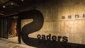 A large, illuminated '2' sign with the word 'roaders' below it, set against a wooden wall with a stone accent. - Roaders Hotel Zhonghua (Taipei)