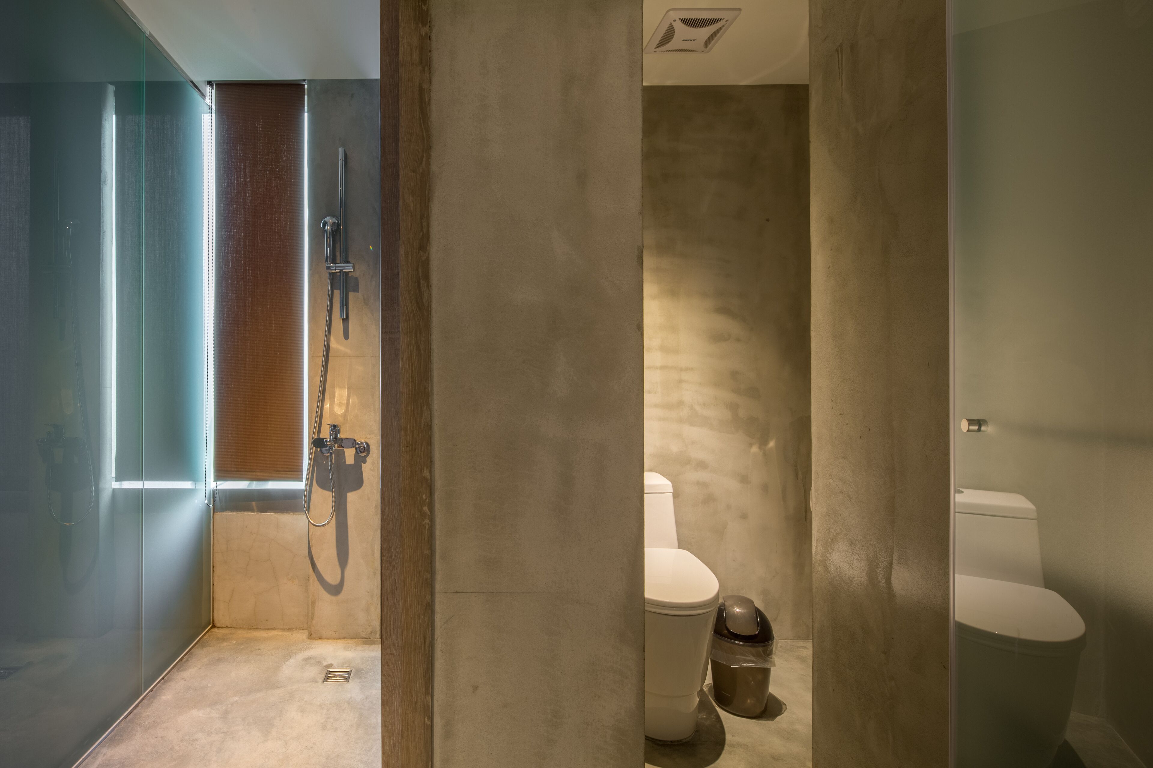 A modern bathroom with a glass shower enclosure, a toilet, and a bidet.