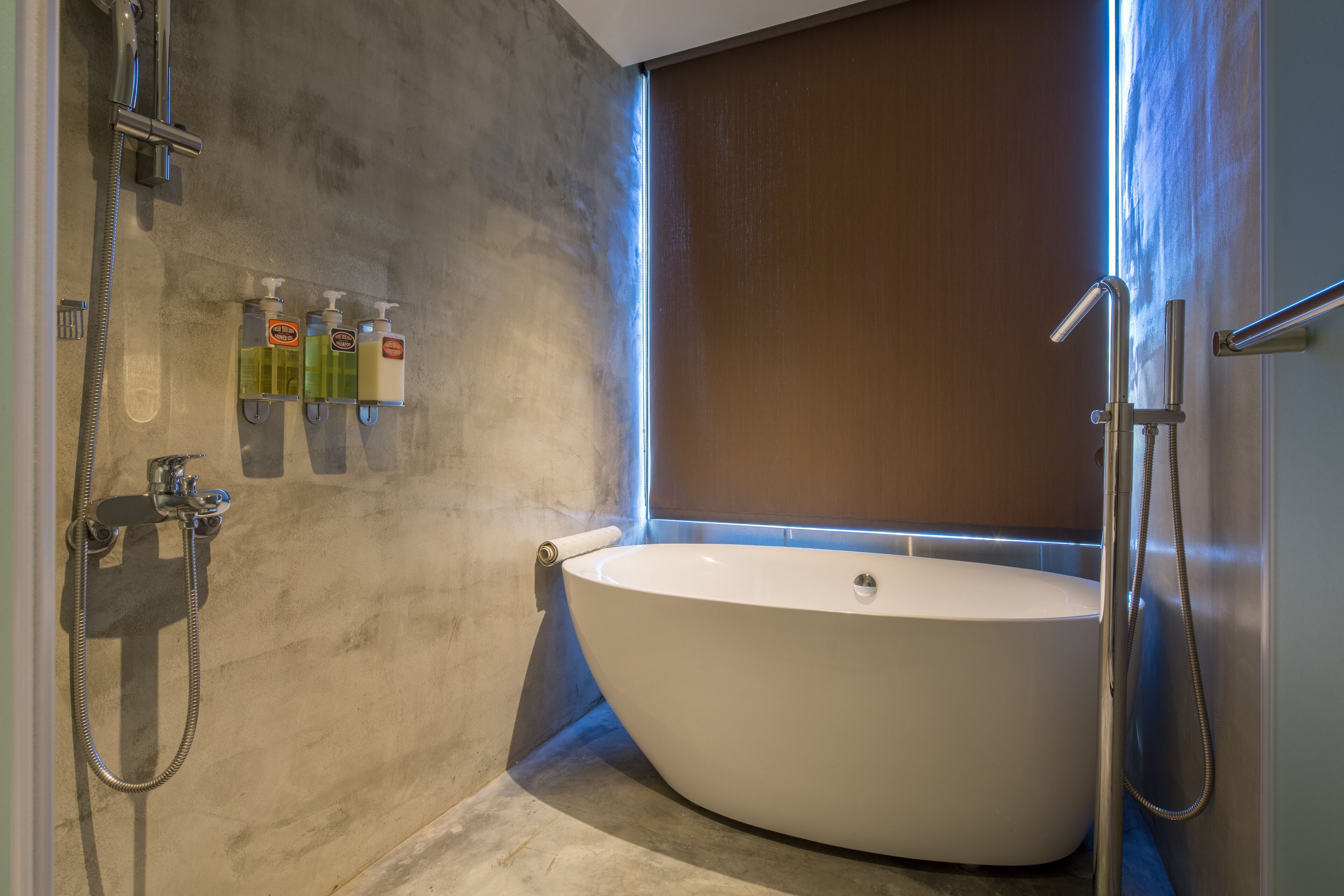 A modern bathroom with a freestanding bathtub, a handheld showerhead, and a built-in toilet.