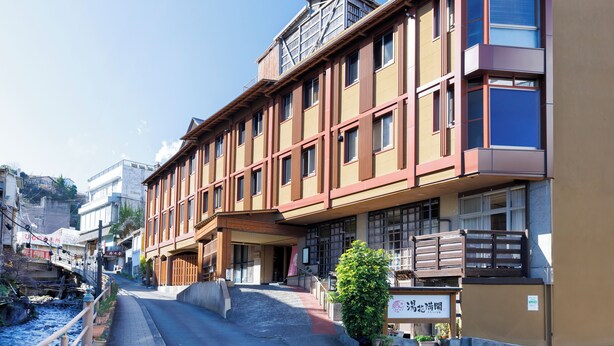 A multi-story hotel with a traditional facade, a covered entrance, and a small garden area. - YUBANA MANKAI (Higashiizu)
