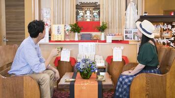 A traditional Japanese-style room with tatami mats, wooden furniture, and a low table with a vase of flowers.