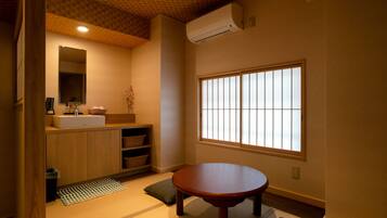 A traditional Japanese-style room with tatami flooring, a wooden table, a built-in shelf, a sink, and a window with shoji screens.