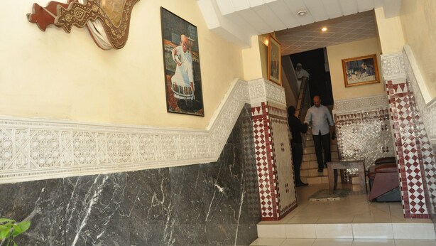A staircase with intricate white and red tile patterns, leading to a room with a marble floor and a large decorative mirror. - Hôtel Boustane (Casablanca)