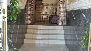 A staircase with patterned walls and a tiled floor, leading to a room with a bed and a painting on the wall. - Hôtel Boustane (Casablanca)