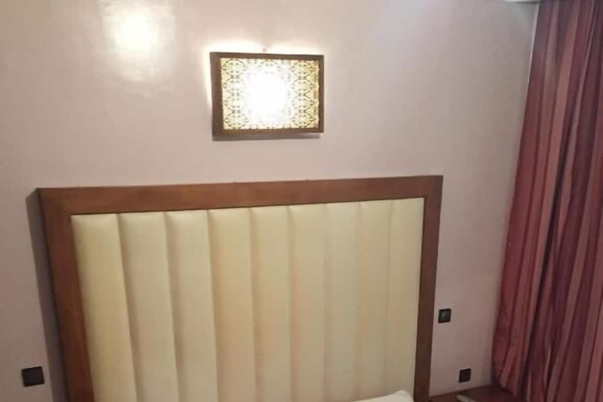A bedroom with a large bed, a wooden headboard, two bedside tables, and a nightstand.