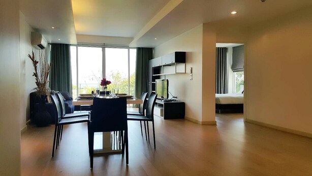 A modern living room with a dining area, large windows, and a flat-screen TV. - Chan Residence Hua Hin (Hua Hin)