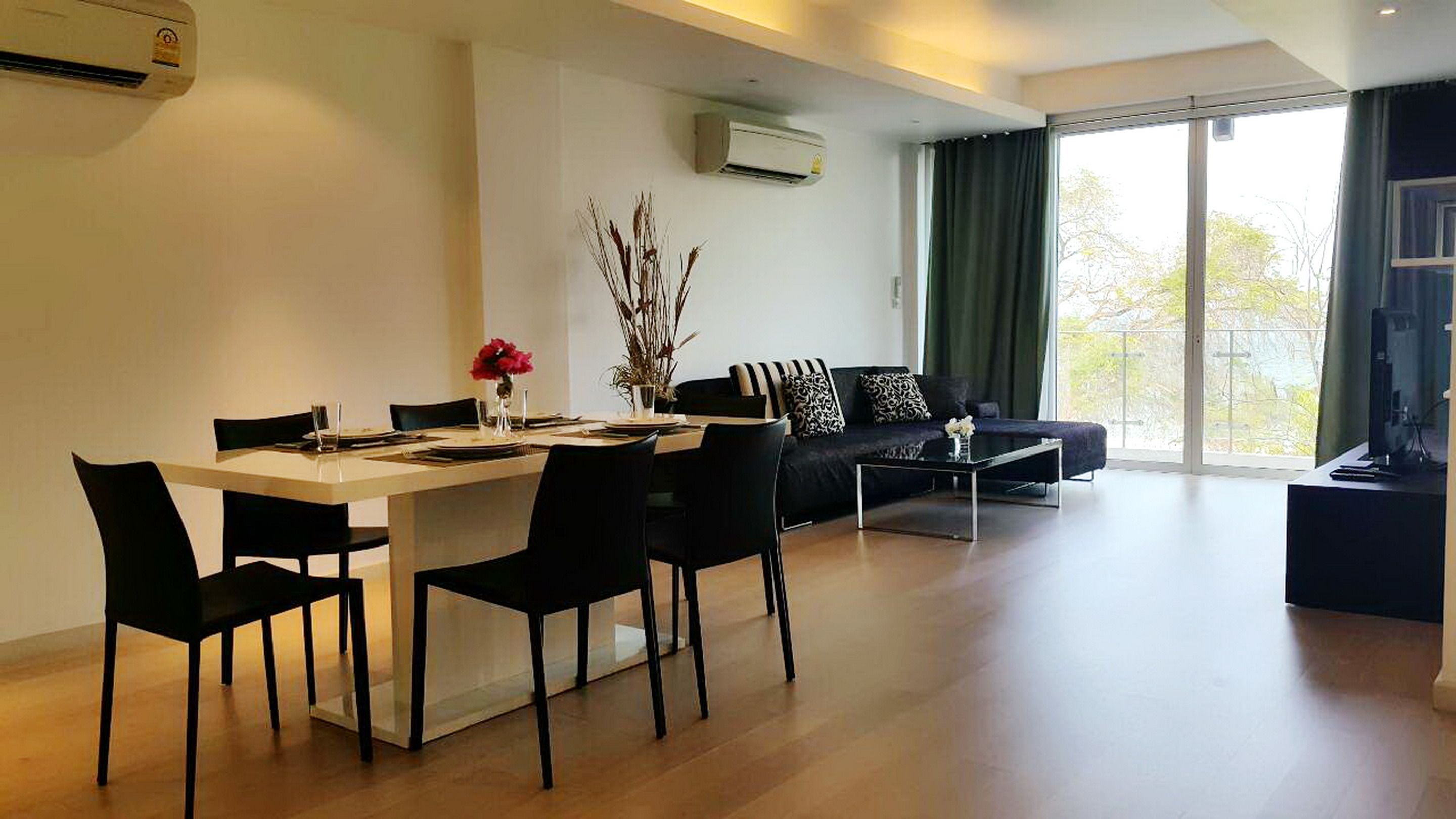 Una sala de estar moderna con comedor, que incluye un sofá, una mesa de centro y una mesa de comedor con sillas.