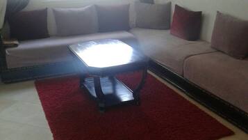 A living room with a sofa, a coffee table, and a red rug.