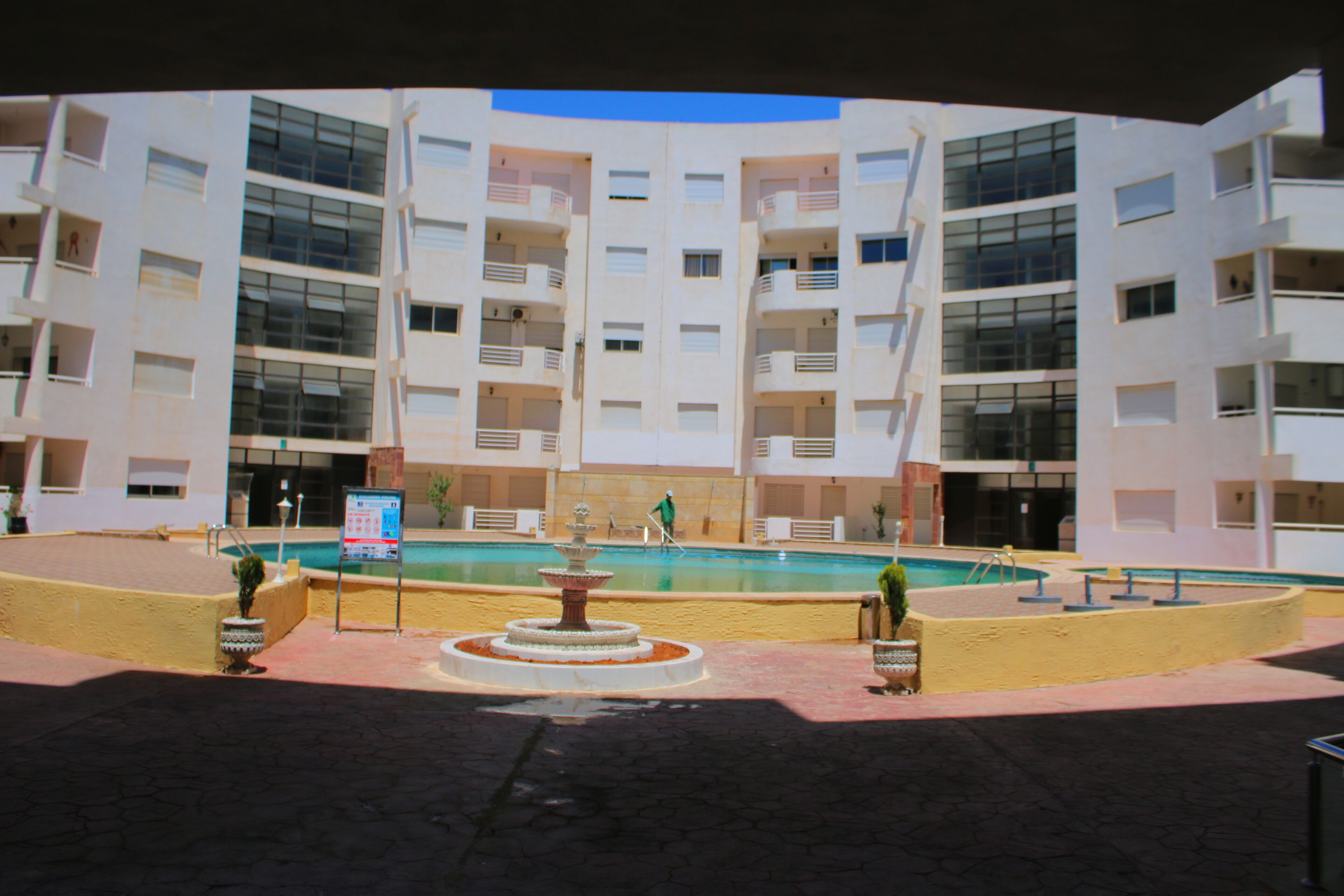 A modern building with multiple balconies and a central courtyard with a fountain.